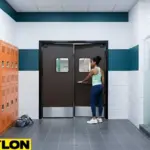 Brown swinging doors in a modern locker room with orange lockers, shown as a user pushes the door open.