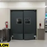 Dark gray double medical lab swinging doors with vision panels and kick plates in a wide corridor.