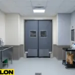 Dark gray double swinging doors in an animal holding room with kennels and sanitation equipment.