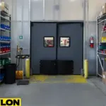 Dark gray swinging door inside a high traffic chemical storage zone with mixed shelving and industrial grade containers.