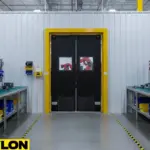 Durable black swinging doors with yellow frame between robotics production zones in a modern industrial workspace