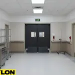 Hospital corridor with black double swinging doors leading to critical care areas.