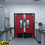 Lab technician opening red PE-Series swinging doors in a chemical lab with organized countertops and storage