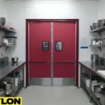 Red double swinging kitchen doors with stainless bottom plates installed in a commercial prep area for smooth staff traffic flow.