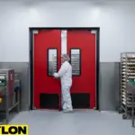 Red industrial swinging door in a processing room with egg conveyors and production staff.