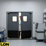 Researcher exiting gray PE-Series swinging doors in chemical lab environment, surrounded by lab equipment and chemicals