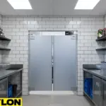 Bar swinging doors in a commercial kitchen with clear visibility panels, allowing safe two-way staff movement.