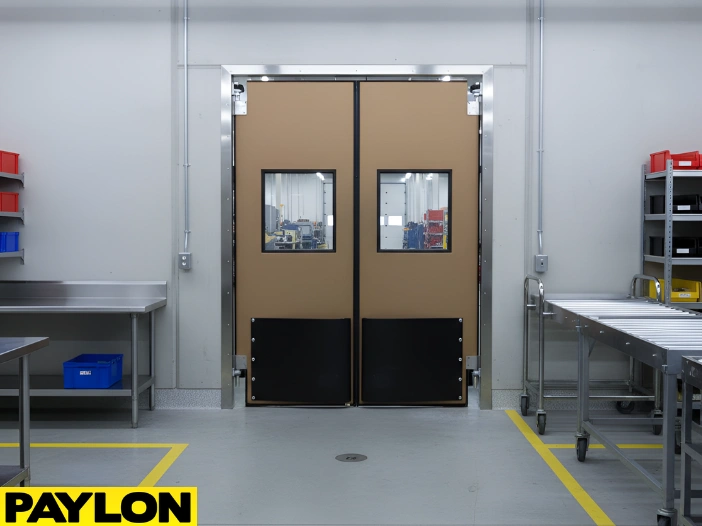 “Beige factory room swinging door with reinforced kick plates and clear vision panels for efficient internal workflow.”