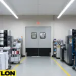 Double gray swinging doors in printing room with organized stacks of paper and ongoing production flow