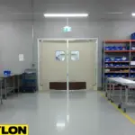 “Factory swinging door in production corridor, allowing staff to move carts and materials seamlessly between work zones.”