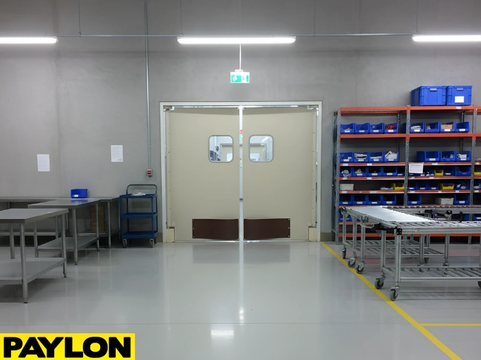 “Factory swinging door in production corridor, allowing staff to move carts and materials seamlessly between work zones.”