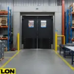 “Heavy-duty black factory room swinging door with vision panels for high-traffic areas and equipment movement.”