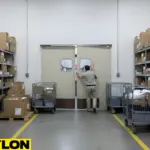 Staff member pushing open beige double swinging doors in busy mail room with carts on both sides