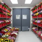 Walk-in floral cooler aisle with flower buckets on both sides and durable cooler doors at the entrance