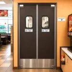 Custom stainless steel swinging door installed in a commercial restaurant kitchen passthrough.