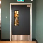 Heavy duty swinging doors installed in a commercial facility, suitable for high-traffic industrial and warehouse environments.