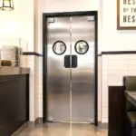 An impact resistant commercial swinging door installed in an industrial or commercial facility doorway.