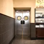 A swinging kitchen door fitted with a vision panel, suitable for use in a commercial restaurant environment.