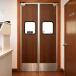 A laminate swing door installed in a restaurant kitchen, providing hands-free passage between the kitchen and dining areas.