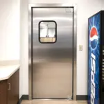 Stainless steel traffic door installed in a restaurant kitchen passthrough or service entrance.