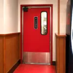 A restaurant swinging door fitted with stainless steel kick plates on the lower panel, suitable for commercial kitchen use.